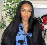 Woman with long black hair wearing a blue and black patterned jacket indoors.